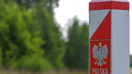 Une borne signalant l'entrée sur le territoire polonais, à la frontière entre la Pologne et la Biélorussie. (ARTUR WIDAK / NURPHOTO / AFP)