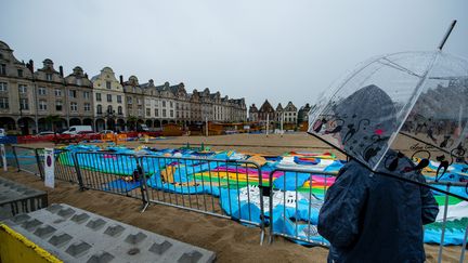 Une passante observe une plage artificielle installée pour l'été à Arras (Nord), fermée à cause de la pluie, le 10 juillet 2017. (MAXPPP)