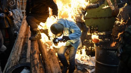 Un manifestant pris dans le feu, alors qu'il se trouve derri&egrave;re une barricade &eacute;rig&eacute;e &agrave; Kiev (Ukraine), jeudi 20 f&eacute;vrier. (BULENT KILIC / AFP)