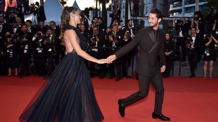 Main dans la main, Pierre Niney et son épouse, l'actrice australienne Natasha Andrews, semblent tout droit sortis d'un conte de fée. L'ancien pensionnaire de la Comédie-Française a un rôle central dans "Mascarade" présenté hors-compétition ce 27 mai.&nbsp; (LIONEL HAHN / GETTY IMAGES EUROPE)