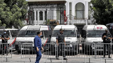 Un homme passe devant des membres des forces de sécurité tunisiennes qui montent la garde devant le siège du parlement au Bardo à Tunis, le 31 juillet 2021. (FETHI BELAID / AFP)