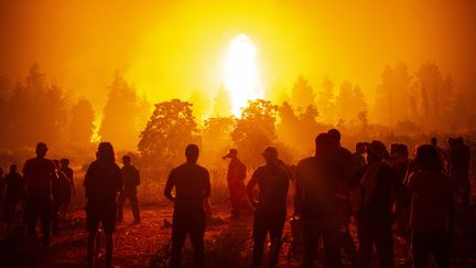 Des jeunes et des volontaires locaux se rassemblent pour soutenir les pompiers lors d'un incendie de forêt à côté du village de Kamatriades, près d'Istiaia, dans le nord de l'île d'Eubée (Grèce), le 9 août 2021. (ANGELOS TZORTZINIS / AFP)