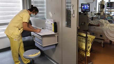 Un soignant remplit des documents près de la chambre d'un patient atteint du Covid-19 dans le service de réanimation de l'hôpital de Saint-Pierre&nbsp;à La Réunion, le 30 juillet 2021. (RICHARD BOUHET / AFP)