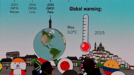 Des visiteurs échangent devant un écran géant représentant le réchauffement climatique, lors de la COP23 à Bonn (Allemagne), le 8 novembre 2017. (PATRIK STOLLARZ / AFP)