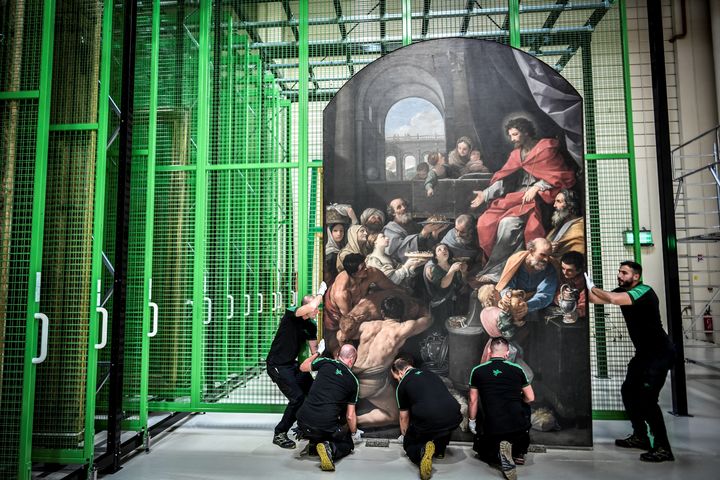 Des ouvriers transportent un tableau sur le chantier de restauration des peintures de la cathédrale Notre-Dame de Paris, le 6 septembre 2022. (STEPHANE DE SAKUTIN / AFP)