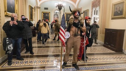 Jake Angeli, membre du mouvement conspirationniste QAnon, pose dans un couloir du&nbsp;Capitole, à Washington, le 6 janvier 2021. (MANUEL BALCE CENETA / AP / SIPA)