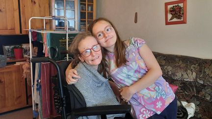 Isaline, 13 ans, et Aurélie, 41 ans, sa maman lourdement handicapée à cause d'un caillot sanguin dans le cerveau, dans le salon de leur appartement à Yerres dans l'Essonne. (SANDRINE ETOA-ANDEGUE / RADIO FRANCE)