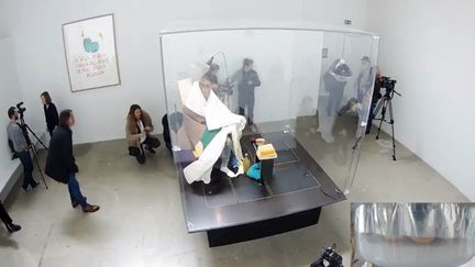 Abraham Poincheval enfermé dans son nid de verre, couvant ses oeufs, au premier jour de sa performance au Palais de Tokyo. (Capture d'écran live YouTube Palais de Tokyo)