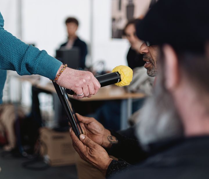 A specialized educator from Samu social hands a microphone to a participant of the Radio mobile Paris program, on March 18, 2022, so that he can read a poem of his creation.  (PIERRE MOREL / FRANCEINFO)