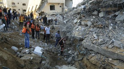 Des secouristes palestiniens inspectent les débris d'un édifice détruit par une frappe de l'armée israélienne, le 13 mai 2021 à Beit Lahia, dans le nord de la bande de Gaza. (QUSAY DAWUD / AFP)