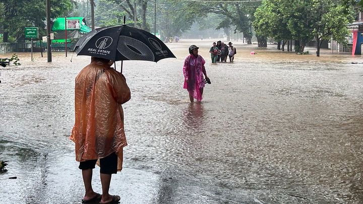 Des personnes marchent dans une rue recouverte par les eaux à Myitkyina, une ville située au nord de la Birmanie, le 2 juillet 2024. (AFP)