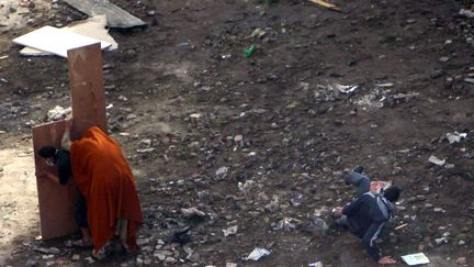 Un manifestant chute tandis qu'un autre se prot&egrave;ge derri&egrave;re un panneau lors d'affrontements avec les forces de l'ordre sur la place Tahrir au Caire (Egypte), le 21 novembre 2011. (AMR DALSH / REUTERS)