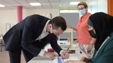 Jordan Bardella signe le registre après avoir déposé son bulletin de vote dans un bureau de Saint-Denis, lors du 1er tour des élections régionales (20 juin 2021). (LUCAS BARIOULET / AFP)