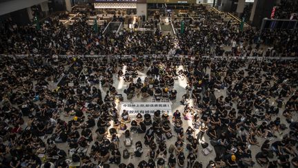 Des manifestants dans le hall de l'aéroport de Hong Kong, le&nbsp;12 août&nbsp;2019.&nbsp; (VERNON YUEN / AFP)