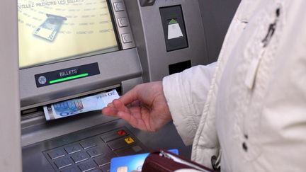 Une personne retire 20 euros à un distributeur automatique de billets, à Toulouse (Haute-Garonne). (MAXPPP)