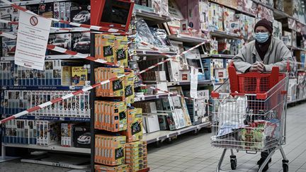 Une cliente d'un supermarché passe devant un rayon de produits non essentiels fermé, le 4 novembre 2020. (PHILIPPE LOPEZ / AFP)