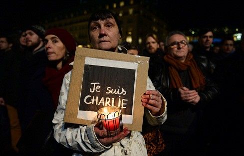 Une femme tient une bougie et une lecture de l'affiche "Je suis Charlie" (Je suis Charlie) lors d'une veillée spontanée devant l'ambassade française le 7 Janvier 2015 à Berlin 
 (JOHN MACDOUGALL / AFP)