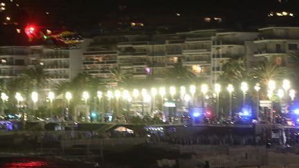 Un hélicoptère survole le site où un camion a foncé dans la foule sur la Promenade des Anglais à Nice (Alpes-Maritimes), le 14 juillet 2016. (VALERY HACHE / AFP)