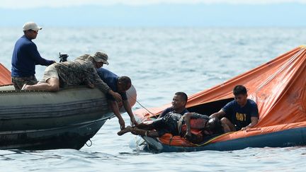 Un membre de la Navy philippine aide des rescap&eacute;s d'un naufrage, le 17 a&ocirc;ut 2013. (TED ALJIBE / AFP)