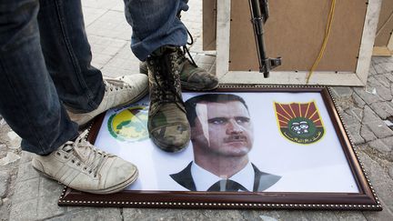 Des rebelles syriens posent sur un portrait du pr&eacute;sident Bachar Al-Assad &agrave; Alep (Syrie), le 20 ao&ucirc;t 2012. (ACHILLEAS ZAVALLIS / AFP)