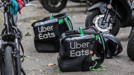 Des sacs de la société Uber Eats destinés à la livraison de nourriture sont déposés au sol à côté de livreurs à deux roues en attente de leur commande, le 24 septembre 2019, à Toulouse (Haute-Garonne). (FREDERIC SCHEIBER / HANS LUCAS / AFP)