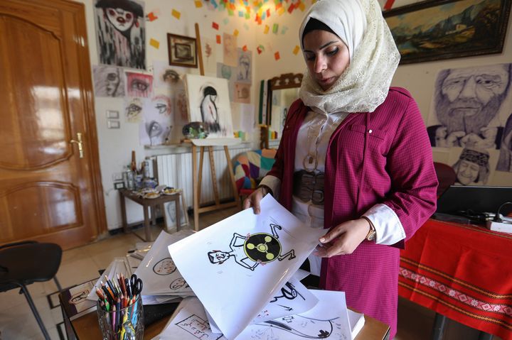 L'artiste syrienne Amani al-Ali, dans son atelier d'Idleb."Ce que j'entends le plus, c'est que je suis une femme et que je ne devrais pas dessiner de telles choses", confie-t-elle. (OMAR HAJ KADOUR / AFP)