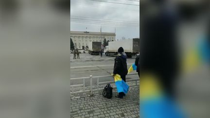 Une image provenant du compte "Les Révélateurs de FranceTV". Les manifestants ukrainiens brandissent leur drapeau face aux soldats russes, place Svobody à Kherson, le 4 mars 2022. (CAPTURE D'ECRAN TWITTER)