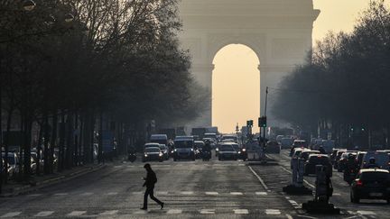 Des voitures circulent près de l'Arc de triomphe, à Paris, un jour de pic de pollution aux particules fines, le 23 janvier 2017. (GEOFFROY VAN DER HASSELT / AFP)