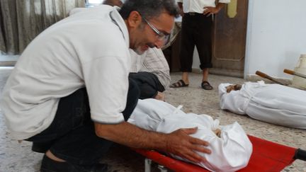 Un homme se penche sur le corps d'un membre de sa famille mort dans une attaque en banlieue de Damas (Syrie), sur une image diffus&eacute;e par l'opposition syrienne le 23 ao&ucirc;t 2013. (AMMAR AL-ARBINI / SHAAM NEWS NETWORK / AFP)