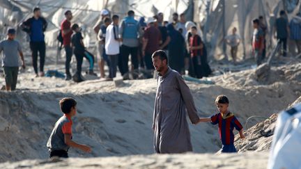 Des Palestiniens aux abords du cratère laissé par la frappe israélienne à Khan Younès, le 10 spetembre 2024. (BASHAR TALEB / AFP)