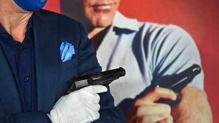 Le pistolet de Sean Connery dans James Bond, présenté à la vente chez Julien's Auctions à Beverly Hills (USA), devant l'affiche de "James Bond contre Dr No"&nbsp; (ROBYN BECK / AFP)