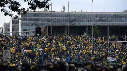 Des partisans de Jair Bolsonaro affrontent les forces de sécurité brésiliennes (au second plan), le 8 janvier 2023. (TON MOLINA / AFP)