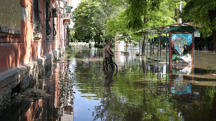 Un habitant de Kherson (Ukraine) dans une rue inondée de la ville, le 6 juin 2023, après la destruction du barrage de Kakhovka, en amont du fleuve Dnipro. (STRINGER / AFP)