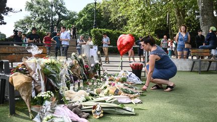 Une femme dépose des fleurs sur l'aire de jeu où des enfants ont été poignardés à Annecy le 8 juin 2023 (OLIVIER CHASSIGNOLE / AFP)