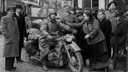 Le&nbsp; 15 mars 1938, un soldat allemand se voit offrir des fleurs dans les rues de Vienne. (STRINGER / FRANCE PRESSE VOIR)