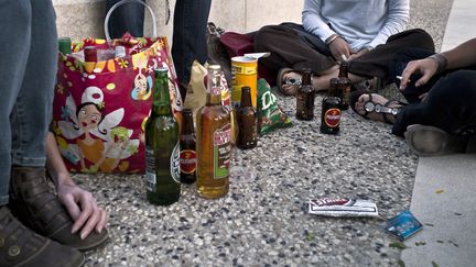 Des gens boivent de l'alcool sur les bords du Rhône à Lyon, le 18 juillet 2018. (JEAN-PHILIPPE KSIAZEK / AFP)