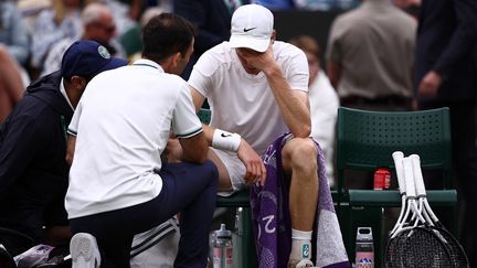 Jannik Sinner, entouré de son staff, lors d'une pause médicale, en quart de finale à Wimbledon, face à Daniil Medvedev, le 9 juillet 2024. (HENRY NICHOLLS / AFP)