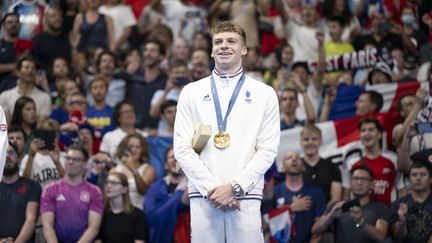 Léon Marchand avec l'une de ses quatre médailles d'or en individuel autour du cou, après le podium du 200 mètres 4 nages, le 2 août 2024 à la Paris La Défense Arena (Hauts-de-Seine). (KEMPINAIRE STEPHANE / KMSP / AFP)