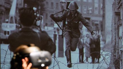 Cette photo célèbre du reporter allemand Peter Leibing, est mise en scène sous trois angles, en mars 2021, dans une exposition consacrée à ce fameux saut au-dessus des barbelés, de la RDA à la RFA, en août 1961, par un jeune policier est-allemand. Le Mur de Berlin commençait à être construit, depuis deux jours... (CLEMENS BILAN / EPA / MAXPPP)