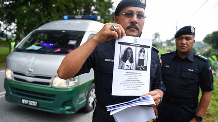 Des policiers malaisiens montrent un avis de recherche concernant Nora Quoirin, le 9 avril 2019 à Seremban. (MOHD RASFAN / AFP)