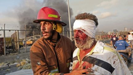 Un pompier prend en charge une victime de l'explosion, le 4 août 2020 à Beyrouth (Liban). (ANWAR AMRO / AFP)