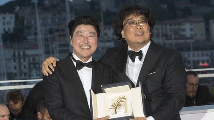 Le réalisateur sud-coréen Bong Joon-ho (à droite) prend la pose avec sa Palme d'Or aux côtés de l'acteur Song Kang-ho, samedi 25 mai 2019 à Cannes (Alpes-Maritimes). (BOESL / DPA / AFP)