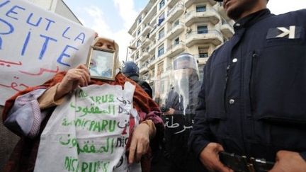 Une femme se tenant près d'un cordon de police pendant la manifestation du 12 février 2012 à Alger (AFP - FAROUK BATICHE)