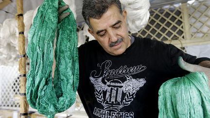 Mohamed al-Rihaoui sort des fils de soie de la teinture
 (LOUAI BESHARA / AFP)