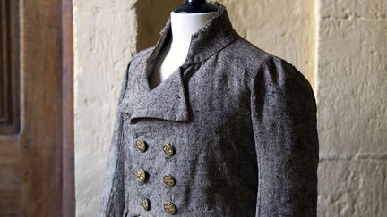 Carmagnole révolutionnaire en habit court dégagé réalisé en cadis de laine brune et chanvre écru (armure toile) avec boutons en laiton martelé.
 (Gilles Martin-Raget)