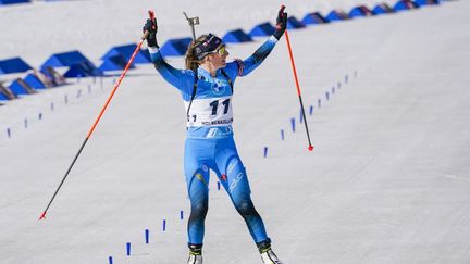 Justine Braisaz-Bouchet lève les bras à l'arrivée de la mass start, le 20 mars 2022, à Oslo-Holmenkollen (Norvège). (TERJE BENDIKSBY / AFP)