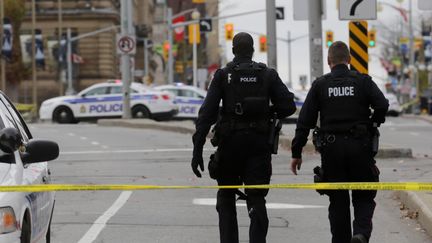 Des policiers marchent dans une rue d'Ottawa apr&egrave;s une fusillade au Parlement canadien, le 22 octobre 2014. (MIKE CARROCCETTO / GETTY IMAGES / AFP)