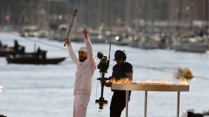 Le rappeur marseillais Jul salue la foule après avoir allumé la vasque dans le Vieux-Port de Marseille, à l'issue du (bref) relais olympique, le 8 mai 2024. (GUILLAUME HORCAJUELO/EPA/MAXPPP)