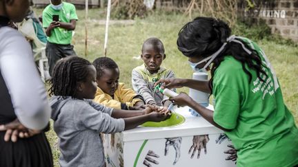 Une femme apprend à des enfants comment se laver correctement les mains devant un hôpital de Nairobi, au Kenya, le 18 mars 2020. (LUIS TATO / AFP)