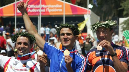 Le 28 août 2024, le VTTiste français Julien Absalon remporte sa première médaille d'or aux JO d'Athènes, aux côtés de l'espagnol Jose Antoni Hermida pour la médaille d'argent et du néerlandais Bart Brentjens. (GREG WOOD / AFP)